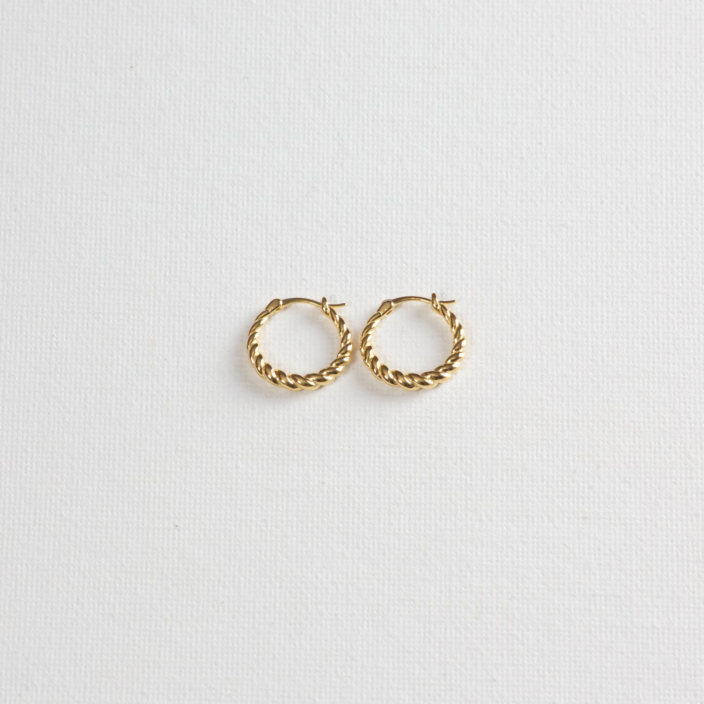 Pasta hoops, gold twisted circular earrings, on a white background. Photographed on a slight angle from the bottom.
