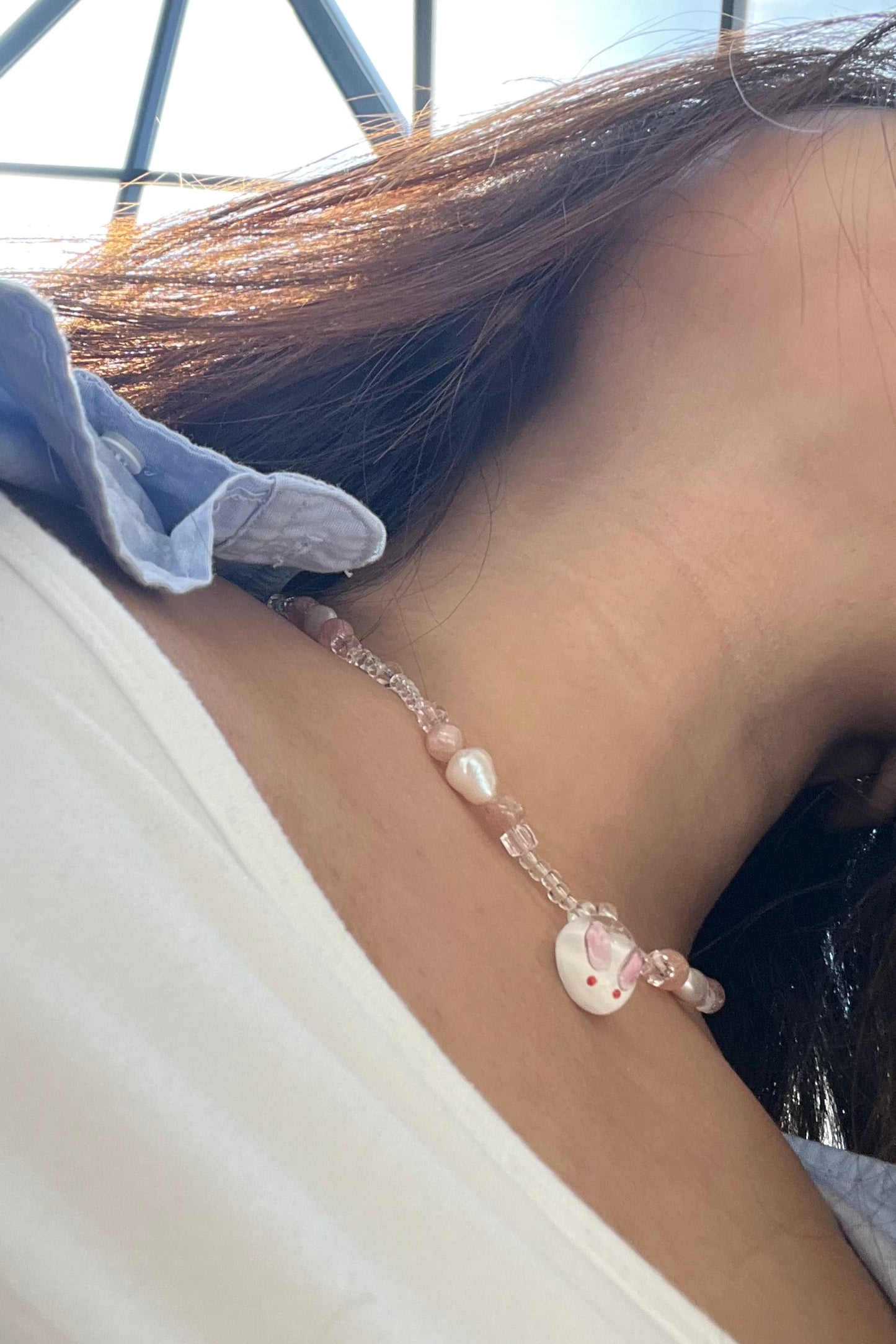 A model wearing the necklace, the photo is taken form the bottom angle, showcasing the cute face of the bunny pendant.