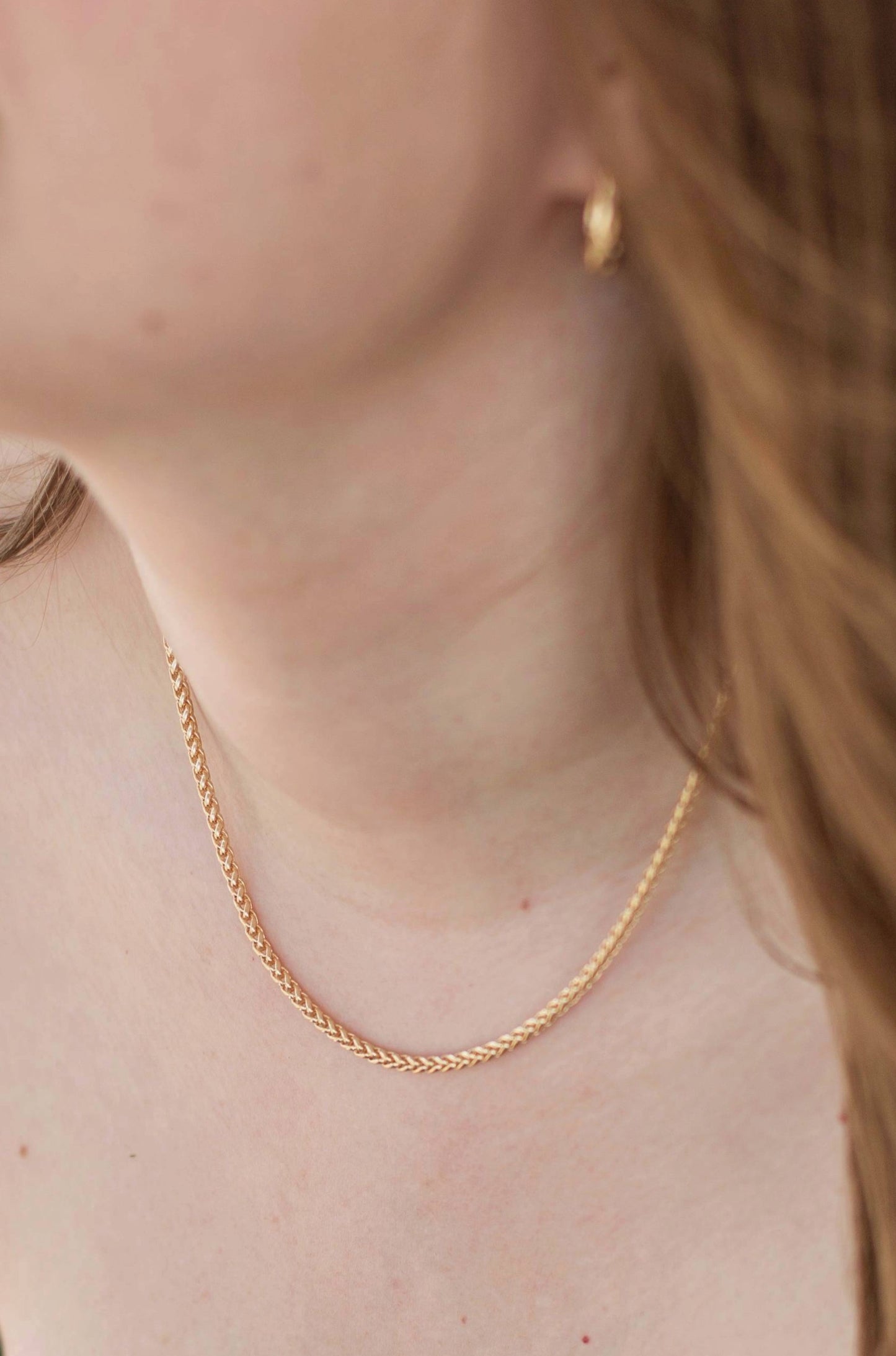 A close up side view of a model wearing the necklace.