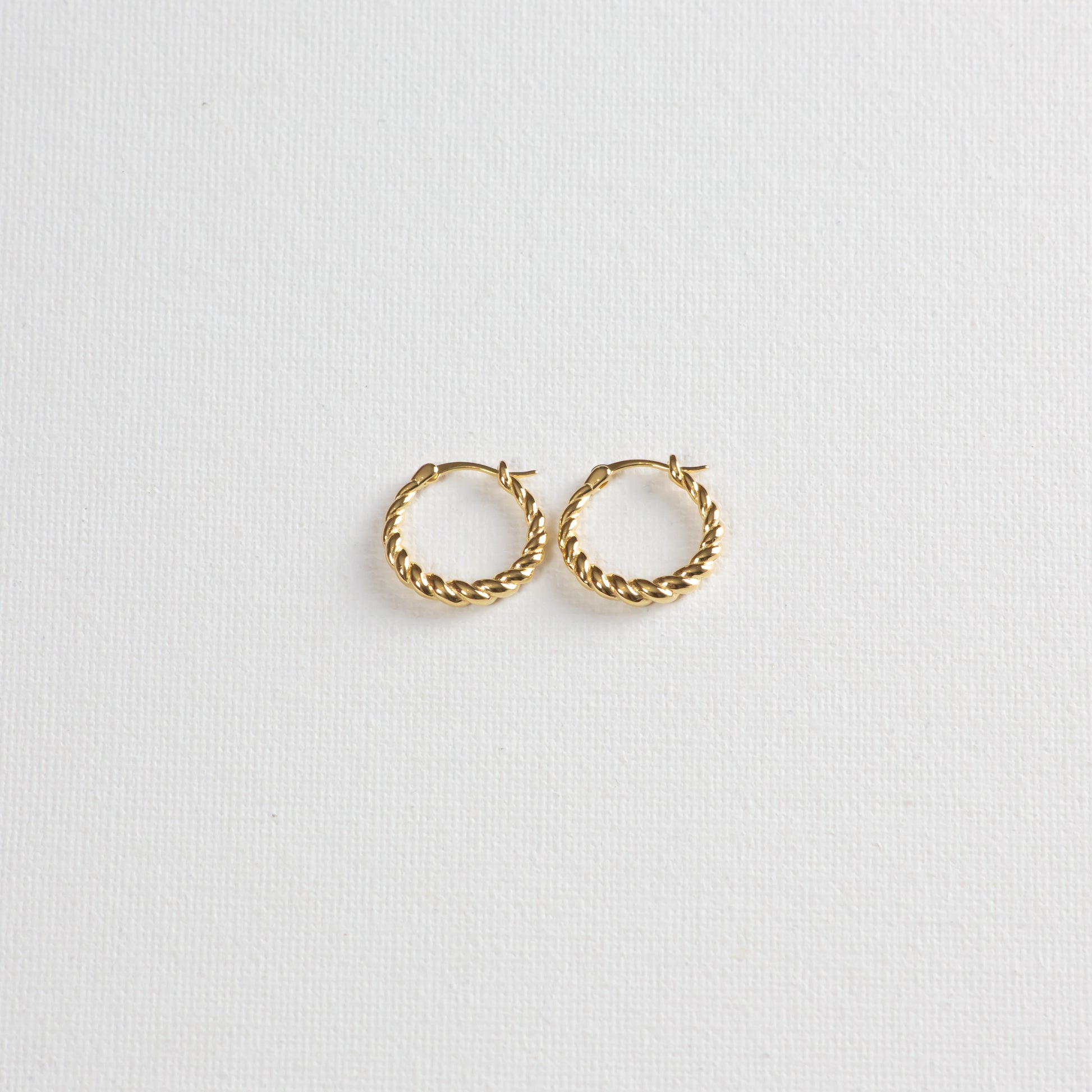 Pasta hoops, gold twisted circular earrings, on a white background. Photographed on a slight angle from the bottom.