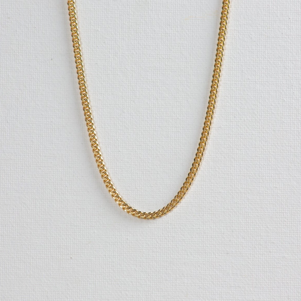 Cuban chain necklace on a clean white background. The necklace features interlocking, tightly-woven links, exuding a sense of elegance and strength.