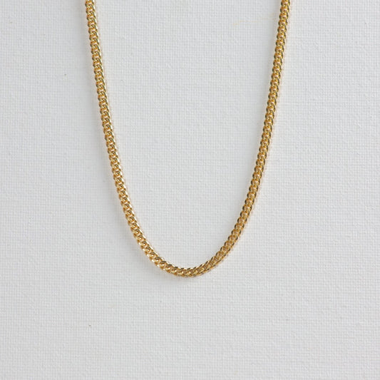 Cuban chain necklace on a clean white background. The necklace features interlocking, tightly-woven links, exuding a sense of elegance and strength.