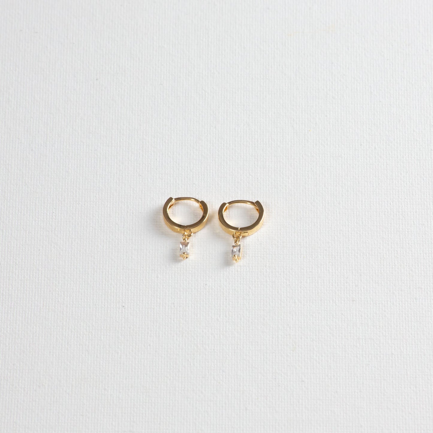 Small hoop earrings with mini baguette crystal charms, showcased on a clean white background.