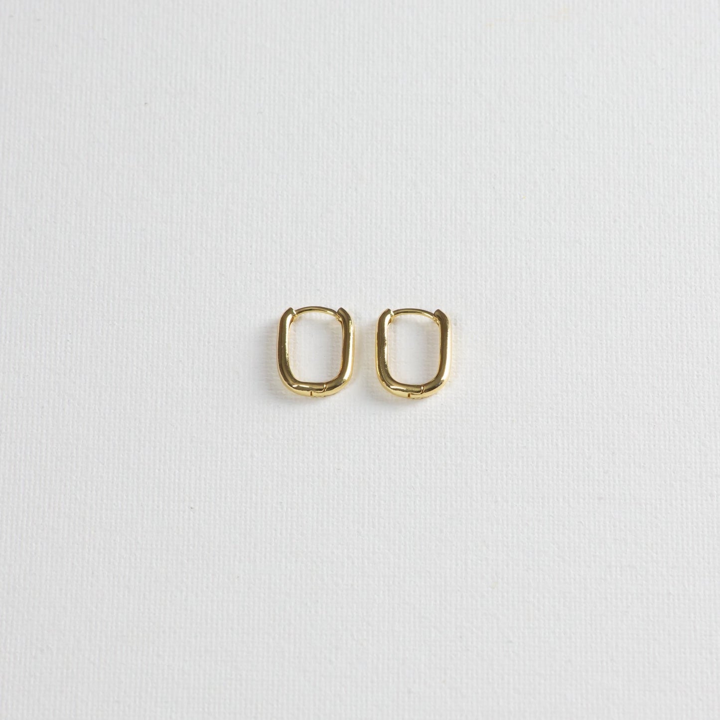 Asa hoops, gold hoops with rounded rectangle shape, on a white background.