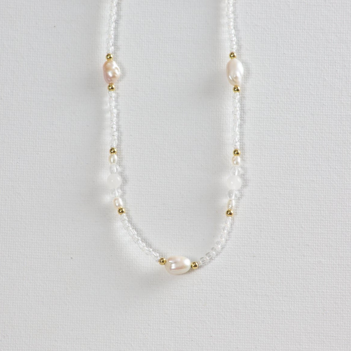 Beaded necklace featuring clear, gold, milky white glass, and pearl beads artfully arranged in alternating patterns.