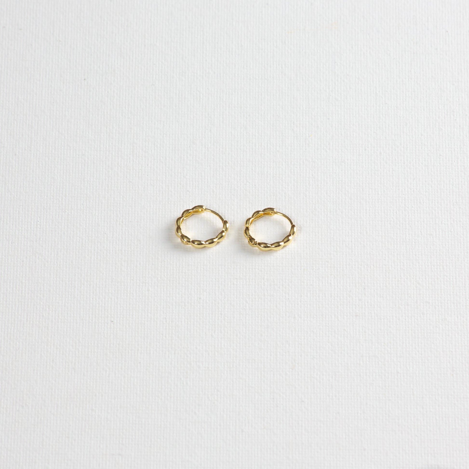 Oryza hoops, gold hoops with rounded textures, photographed on a white background. The photo is taken at a slight angle from the bottom.