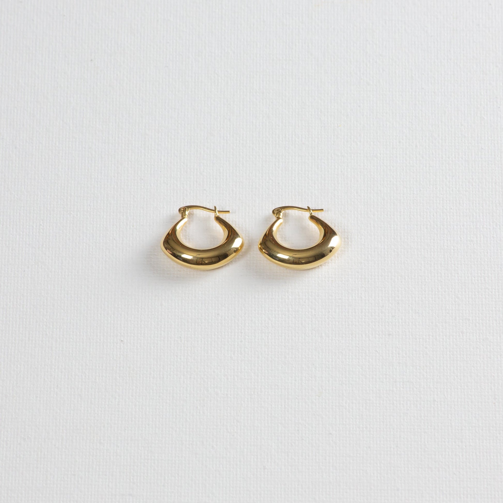 Spade earrings placed on a white background, photographed from a slight angle from the bottom.