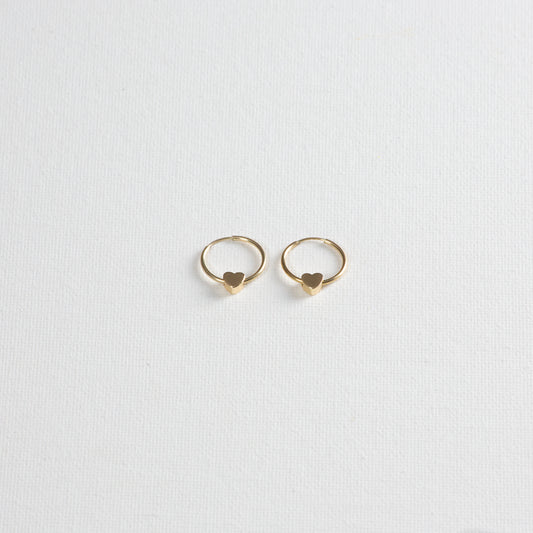 Circle infinity hoop with a small heart charm looped through the hoop. The earrings are photographed on a white background, with a slight angled view from the bottom.