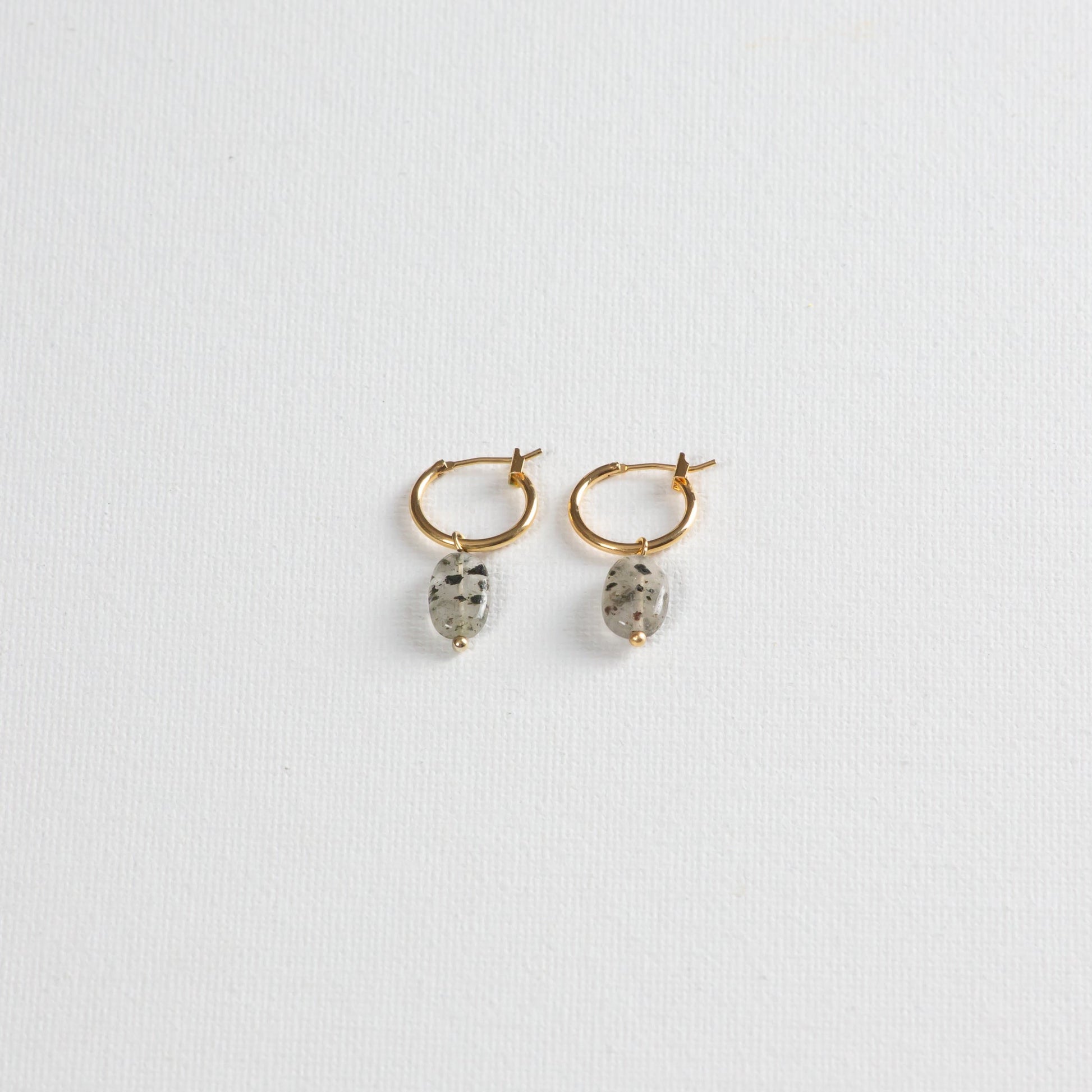 Gold hoop earrings with Dalmatian-like Black Rutilated Quartz Pendants, showcased on a clean white background. 