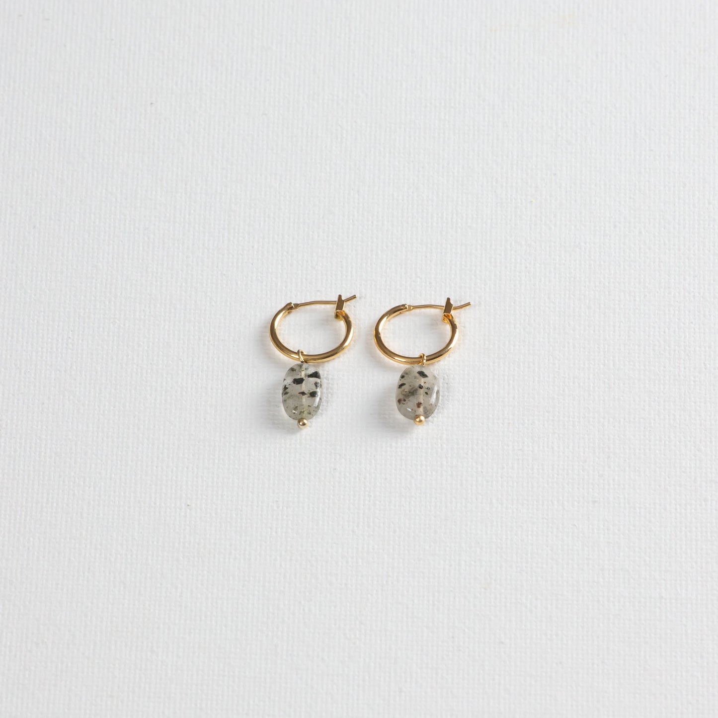 Gold hoop earrings with Dalmatian-like Black Rutilated Quartz Pendants, showcased on a clean white background. 