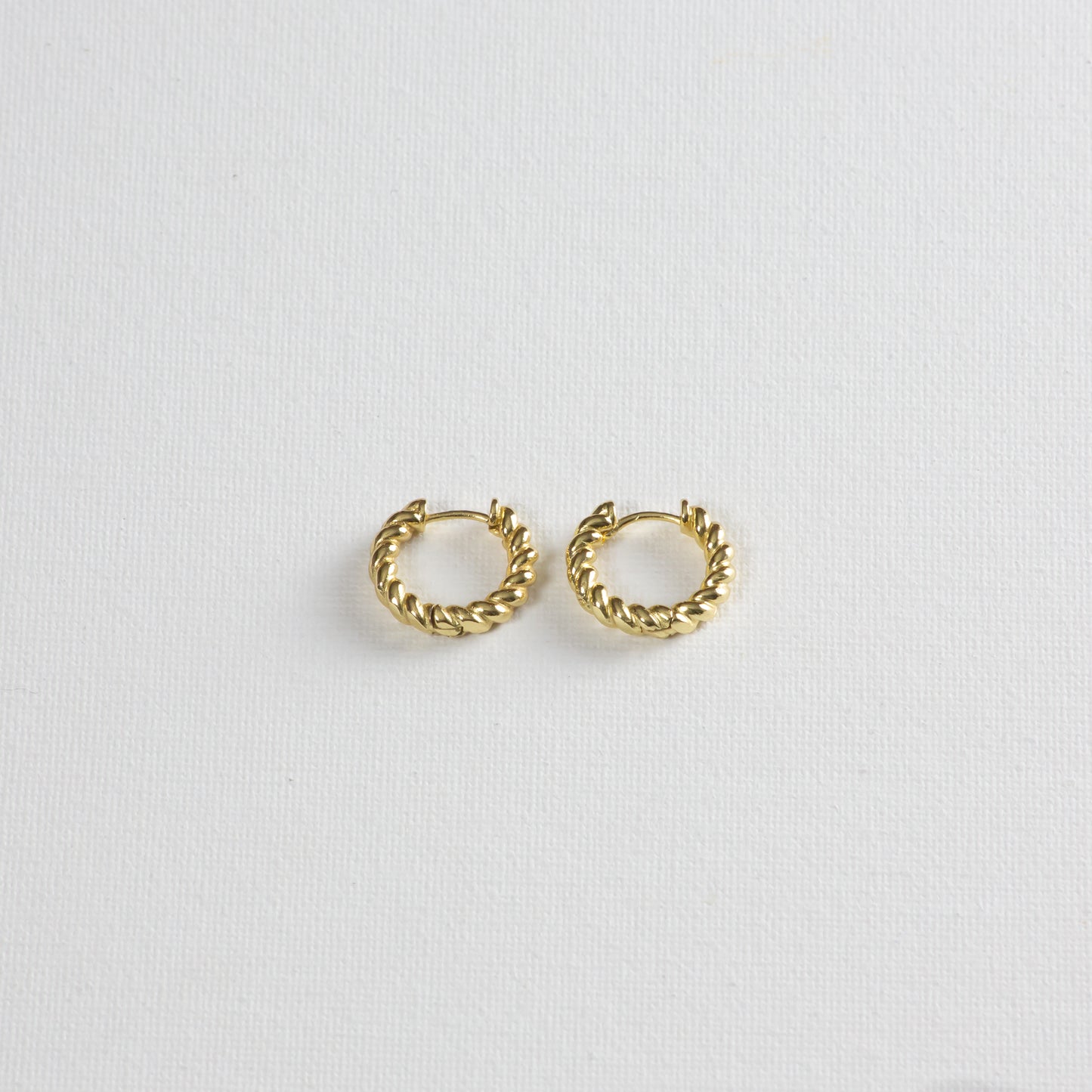 Honey Crueller Hoop Earrings, a gold hoop earrings with twist detail, showcased on a white background, photographed from a slight angle at the bottom.