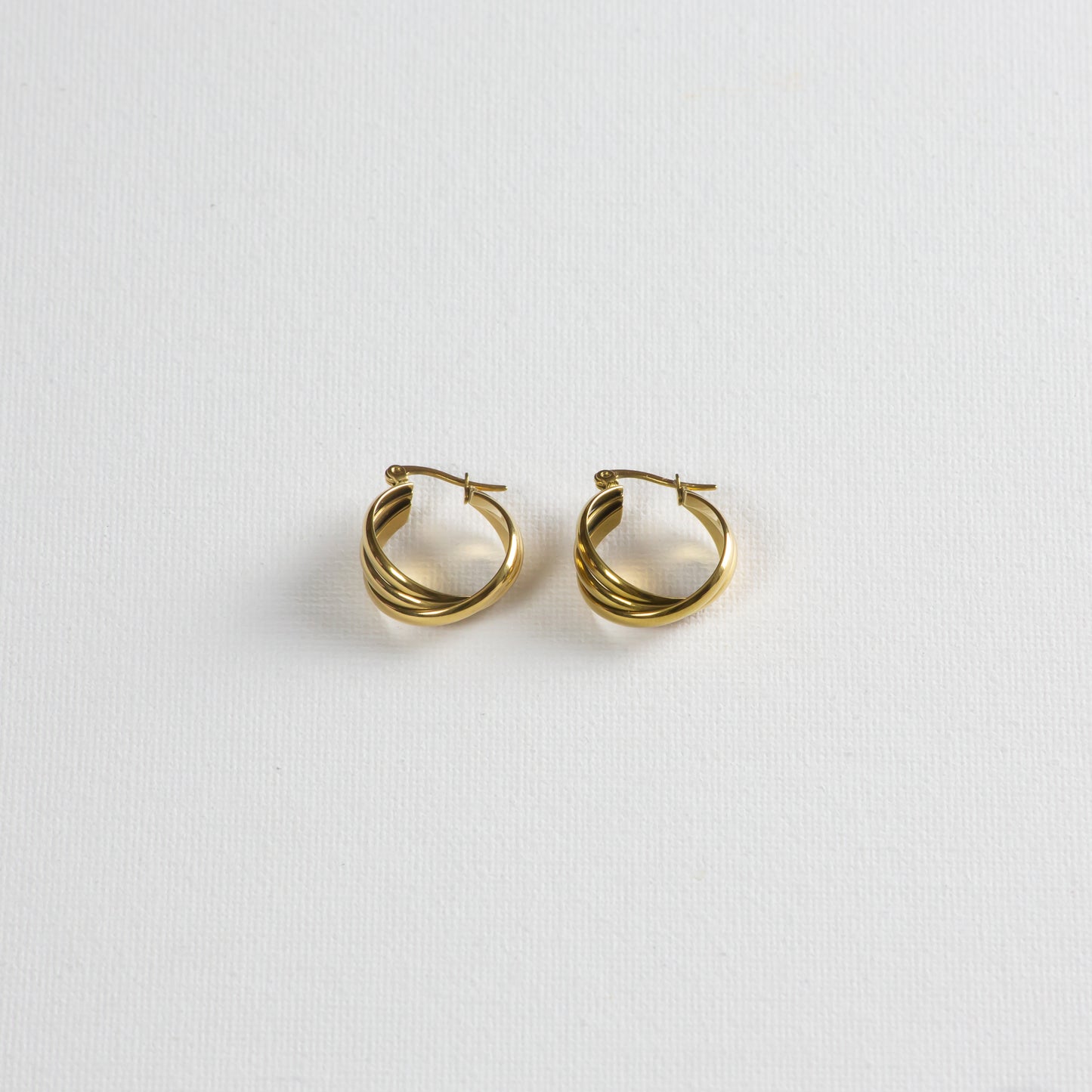 Gold earrings with three strands of small hoops creatively twisted together, showcased on a clean white background. The photo captures the design from a slight angle at the bottom.