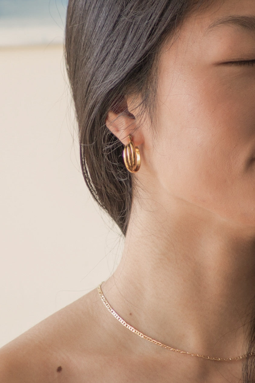 A model wearing the gold earrings. It showcases what the earring looks like from the front.