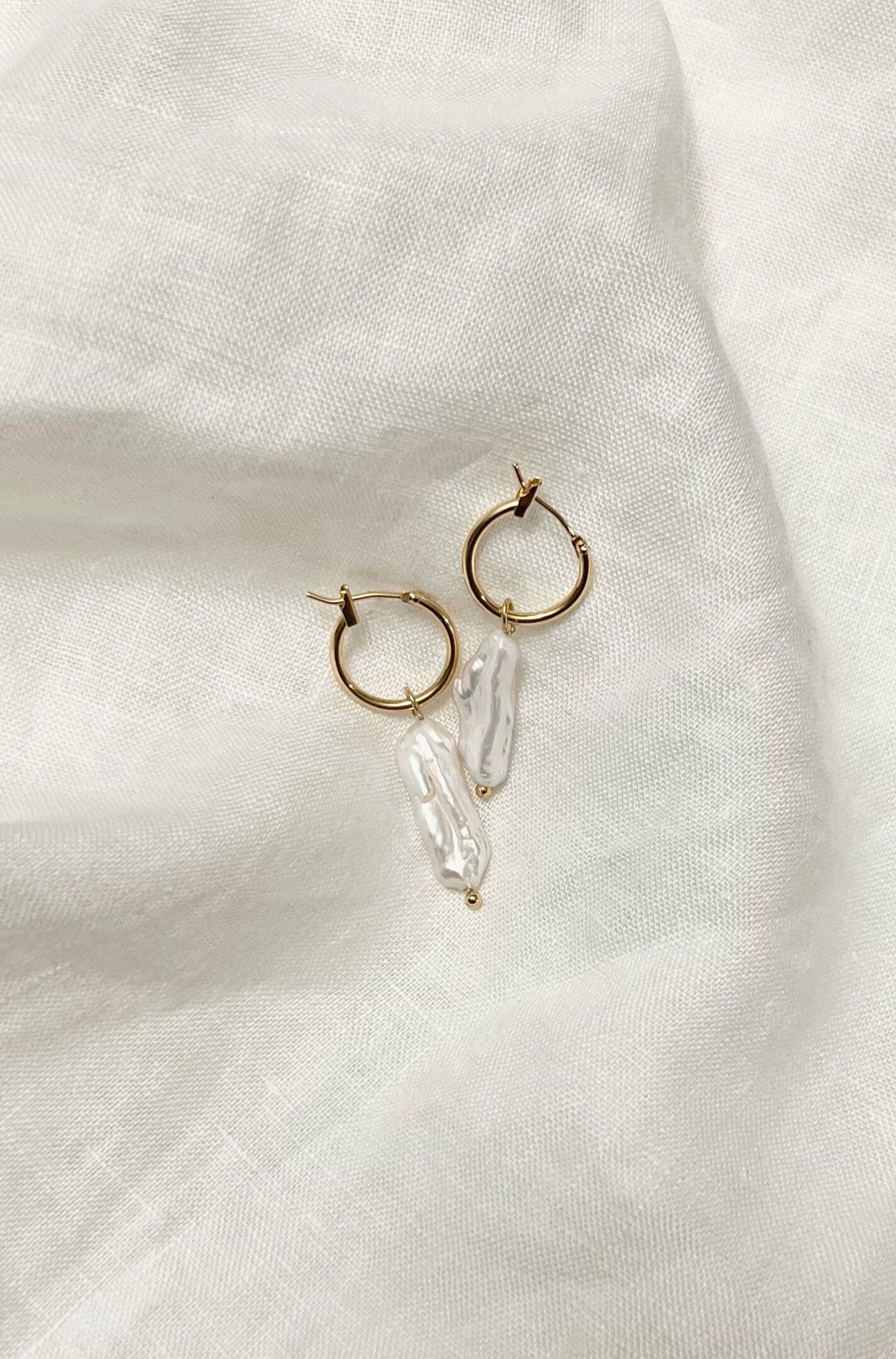 Top view of the earrings, placed on a white linen.