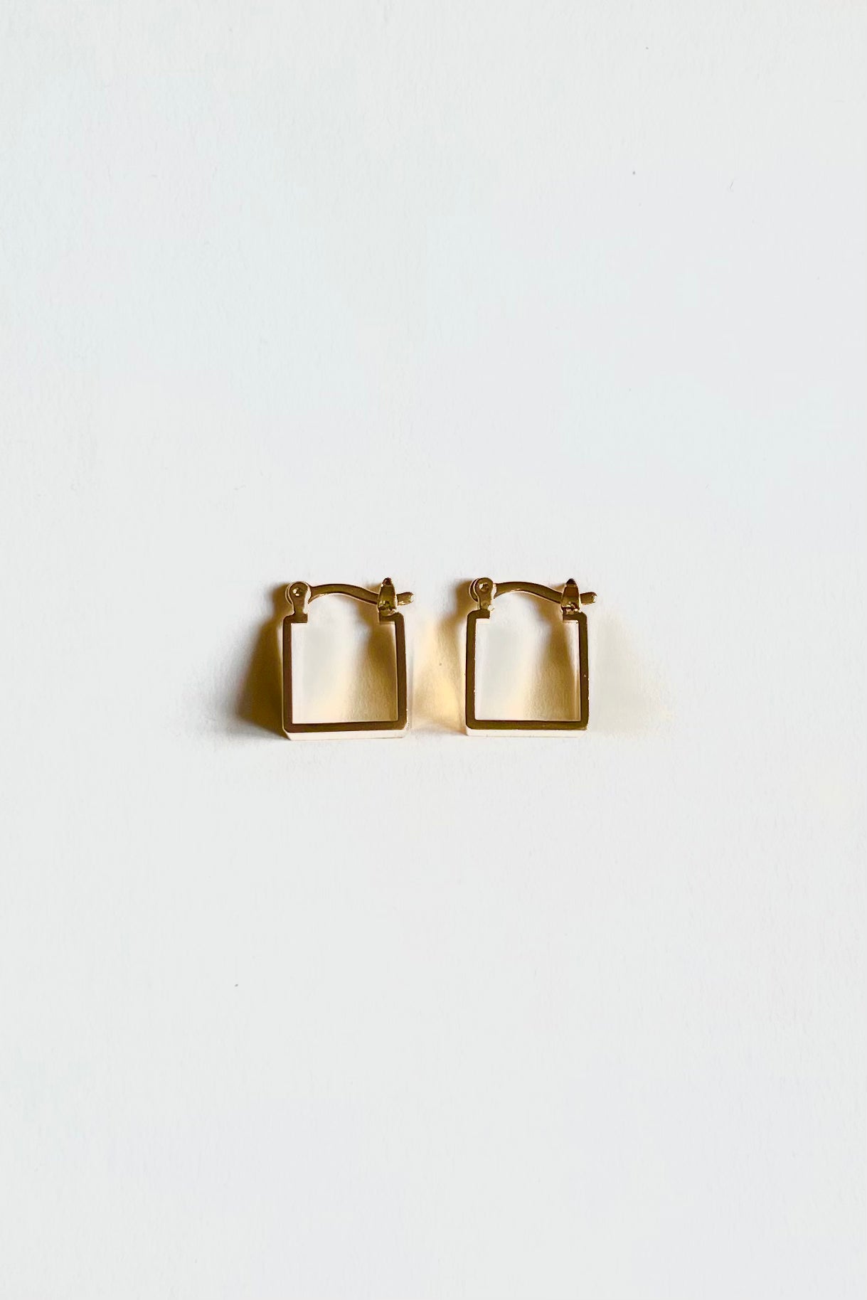 Top view angle of the gold square hoops on a white background.