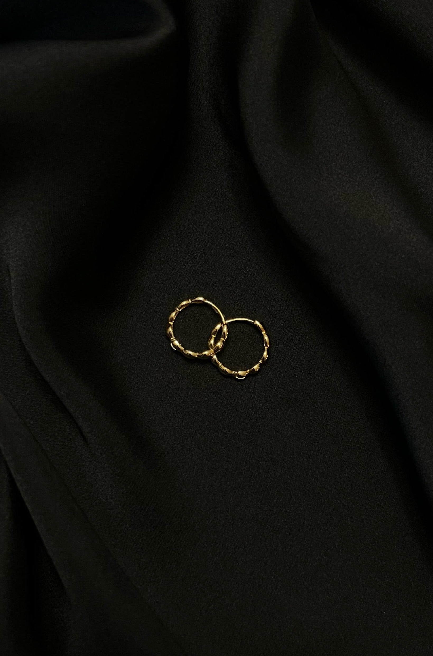 Top view of the Oryza hoops, placed on a black satin fabric.
