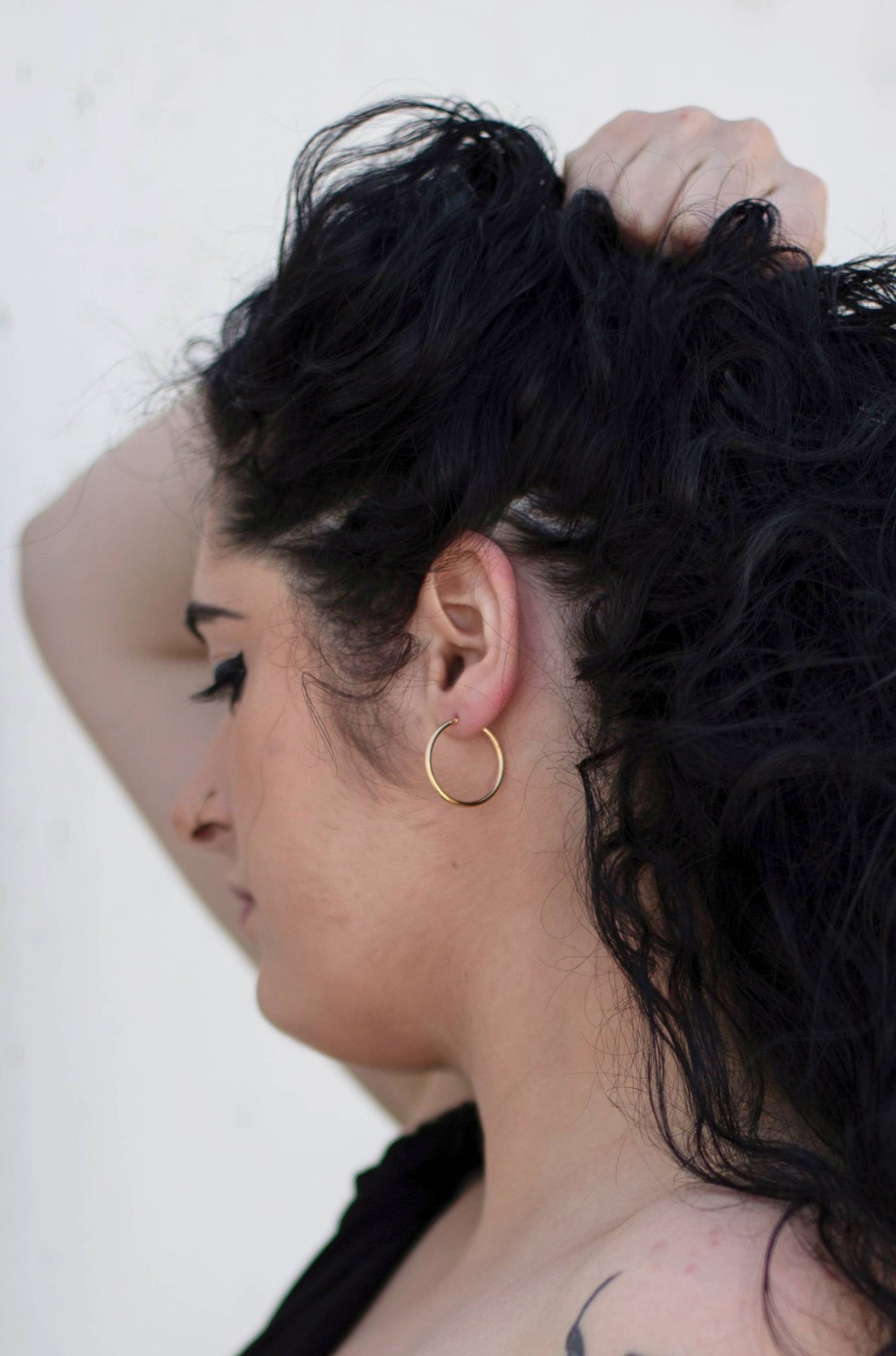 A close up photo of a model wearing Jane hoops, showcasing the size of the hoops.